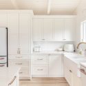 Bright white shaker kitchen with ceiling-height cabinetry, farmhouse sink, quartz counters and a French-door refrigerator.