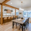 Open dining and kitchen connection with long harvest table, pendant lighting, and seamless transition between cooking and living spaces