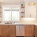 Two-tone kitchen cabinetry with white uppers and maple lower cabinets, paired with quartz countertops and floating shelves.